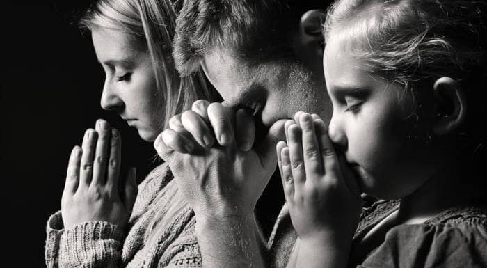 man, woman and child praying