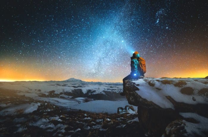 man backpacking looking up at stars