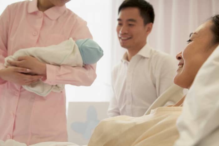 Labor and delivery nurse holding baby for mom and dad