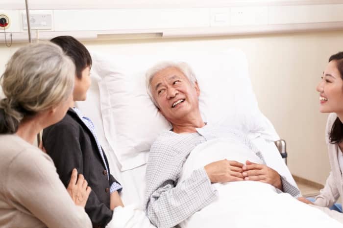 asian grandson talking to grandpa in hospital after heart surgery