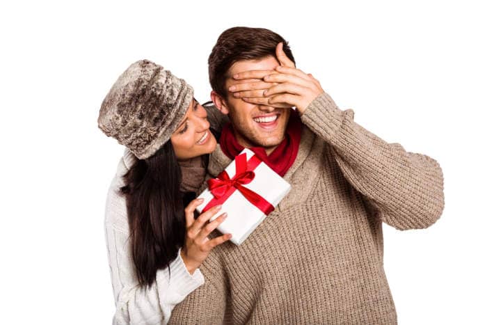 Young woman giving gift to boyfriend on white background