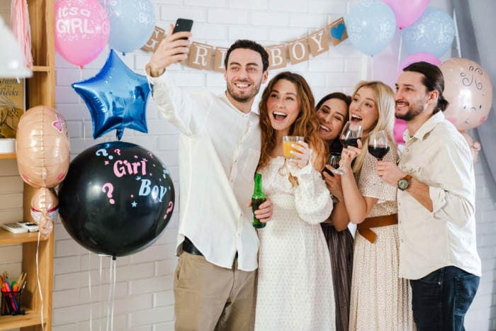 Happy young friends taking selfie photo together during gender reveal party indoors