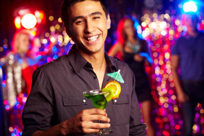 Image of happy guy holding cocktail at party