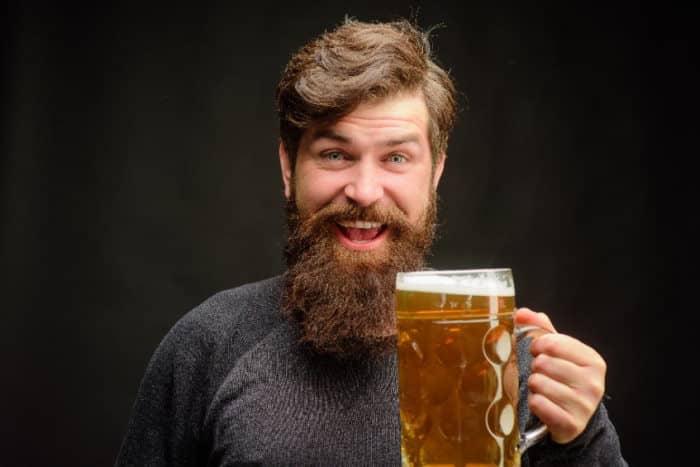 Man with beard holding up a beer