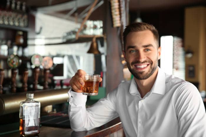Young man drinking scotch in pub