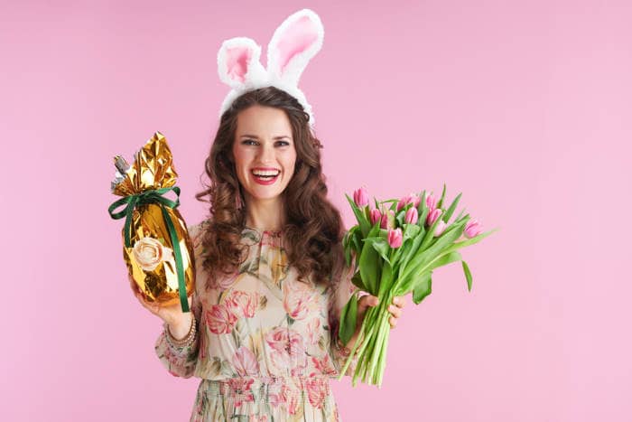 wife holding easter gifts of chocolate bunny and flowers