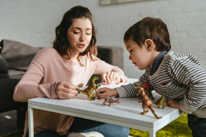 mom and son playing with toy dinosaurs