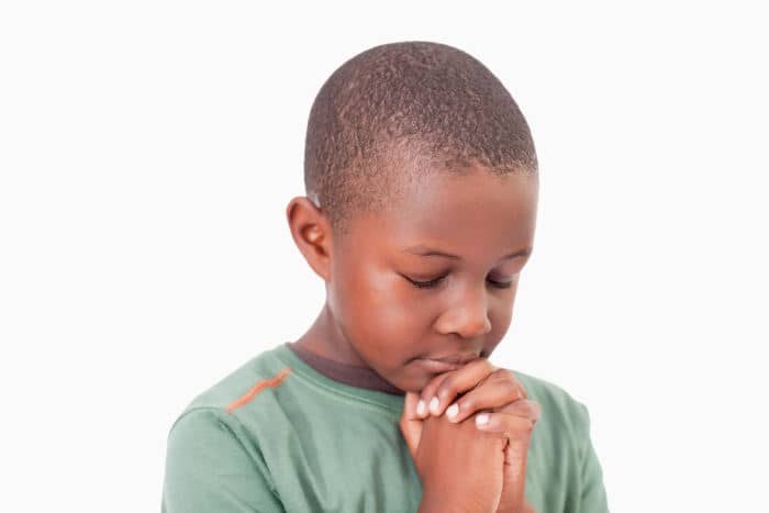 Calm boy praying against a white background