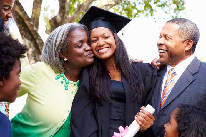 dad and mom hugging their daughter who graduated college