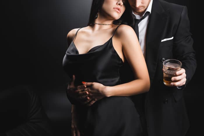 man holding bourbon with sexy girlfriend in his other arm