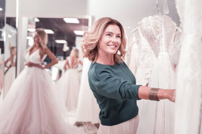 Mother helping daughter shop for wedding dress
