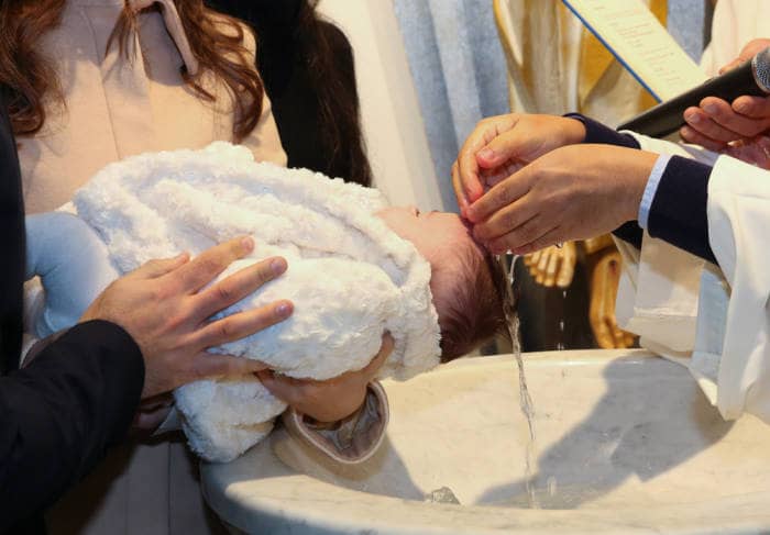 Newborn baby baptism, water with hands of priest.
